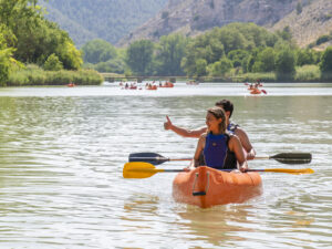 Kayak en río, mujer remando, naturaleza veraniega.