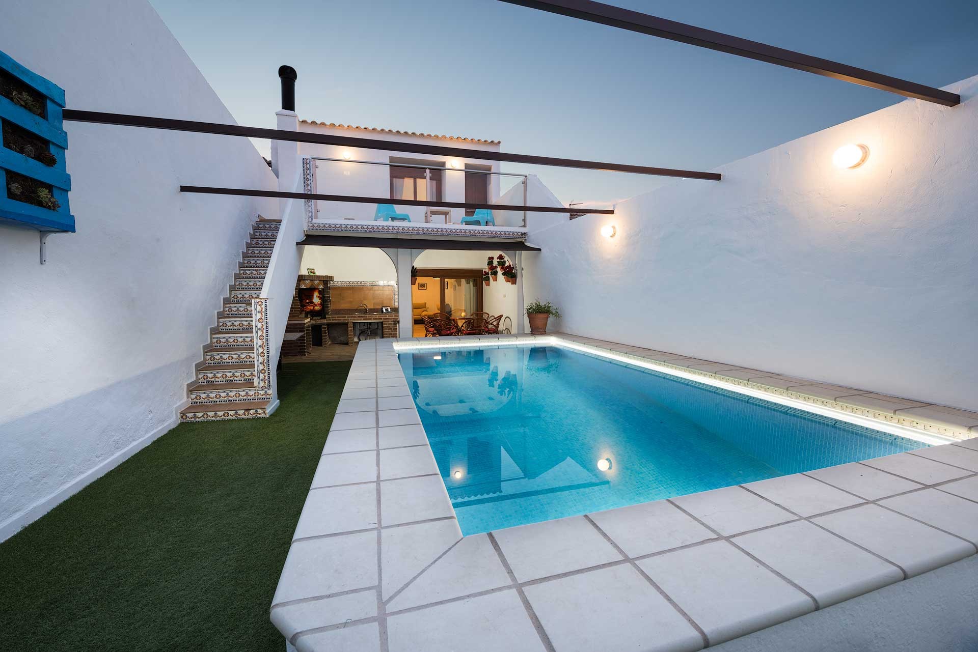 Casa blanca, piscina azul, terraza y escaleras estilo español.