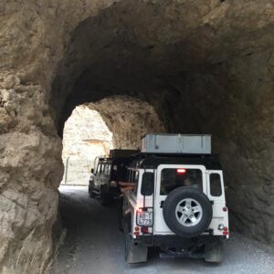 Vehículo pasando por túnel natural en montaña.