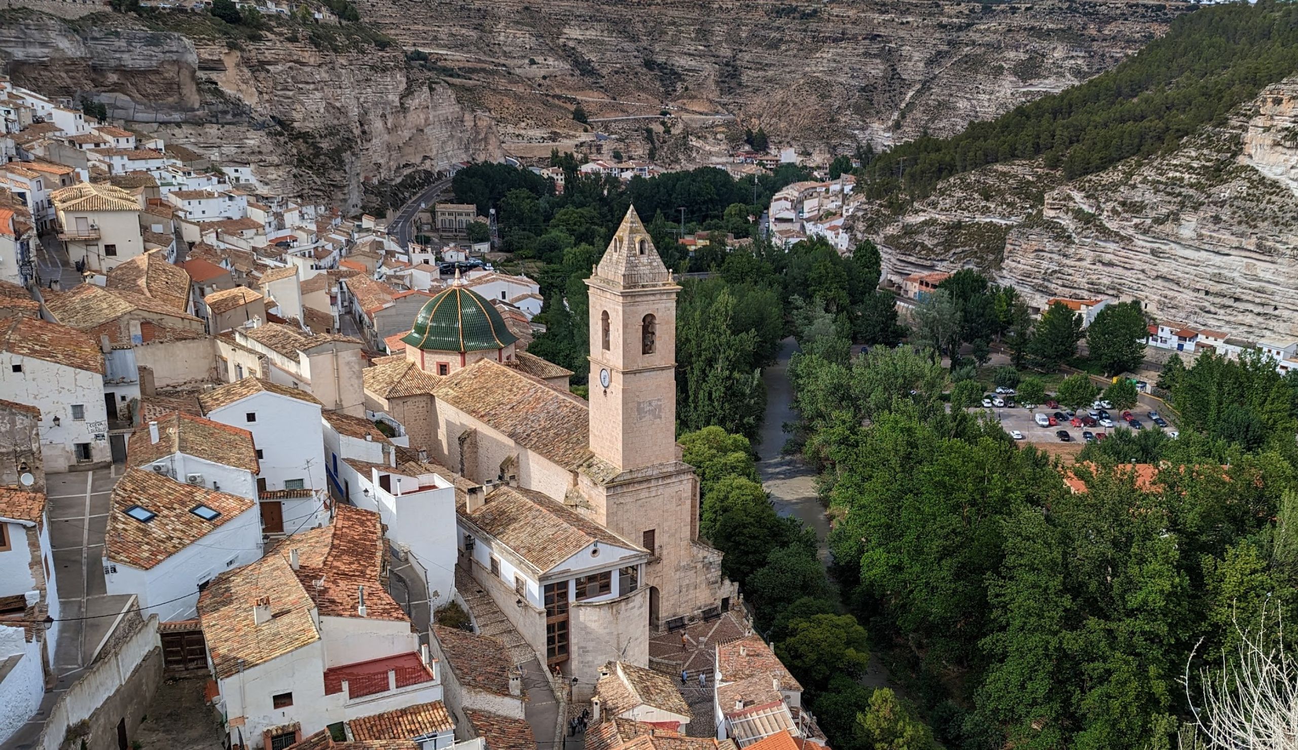 Vista aérea pueblo con iglesia y montañas.